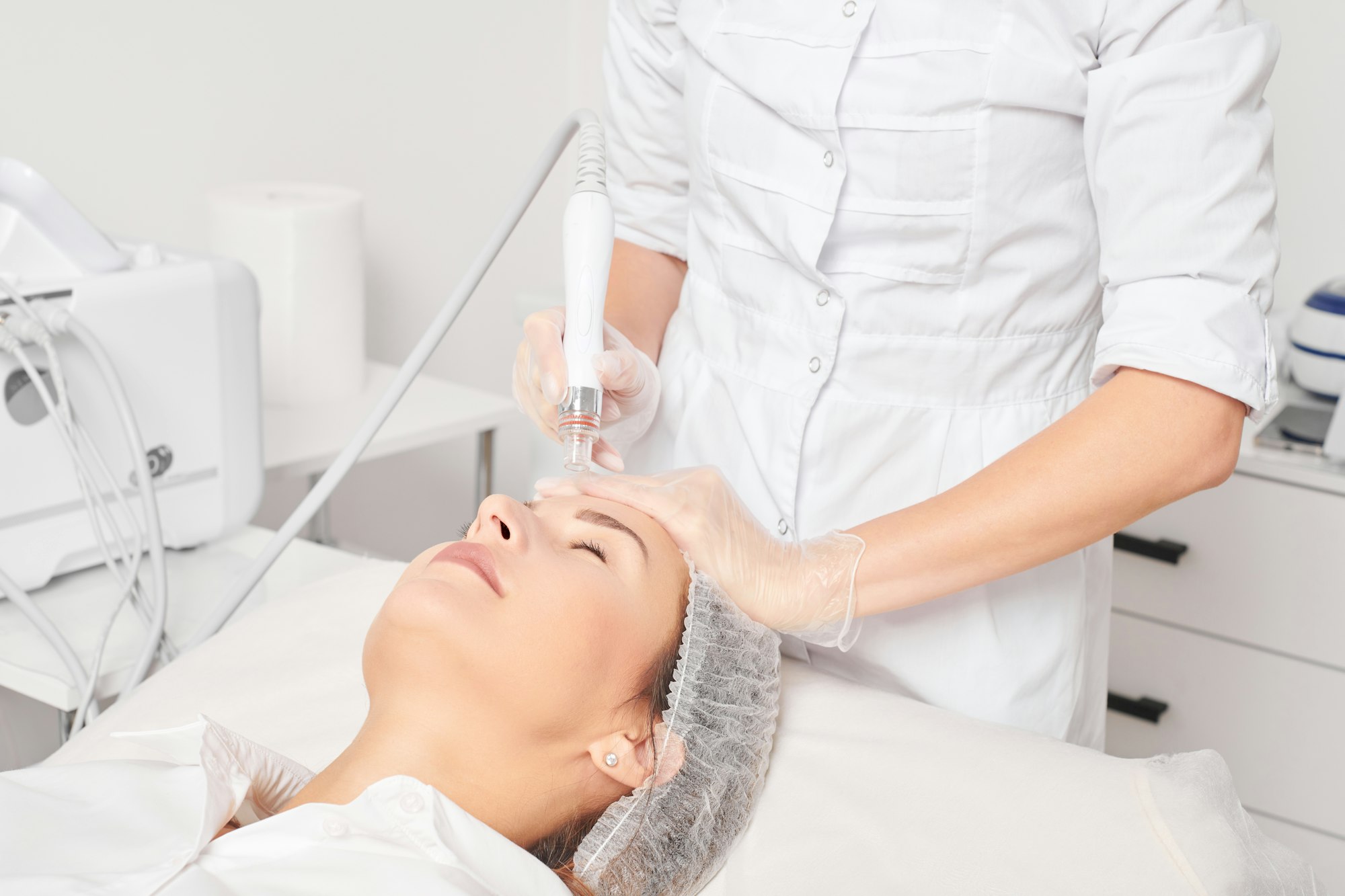 Esthetician performing an AquaFacial exfoliation on a woman's face at Hideaway Wellness & Aesthetics