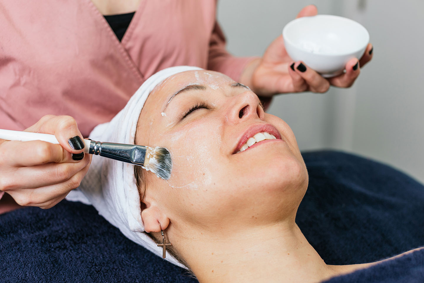 Esthetician brushing on a custom facial mask during a treatment at Hideaway Wellness & Aesthetics